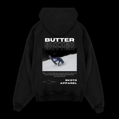 Back of Skoto Butter Board Hoodie – black hoodie with skier buttering graphic, triple “Butter” text design, and Skoto Apparel branding