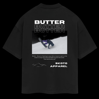 Back of Skoto Butter Tee – black t-shirt featuring skier buttering on snow with bold white “Butter” text and Skoto Apparel branding