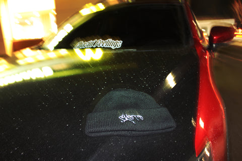 Skoto black beanie on black sports car hood – streetwear beanie with graffiti logo styled on sleek red and black car, night photography aesthetic